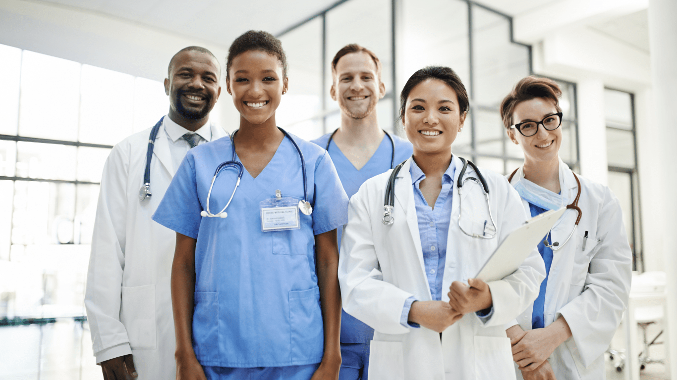 grupo de médicos olhando para a frente e sorrindo, expressando a alegria de acolher e dar uma excelente experiência ao paciente